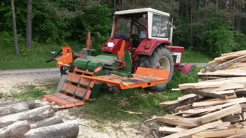 Traktor mit angebautem Sägetisch und geschnittenen Brettern im Wald